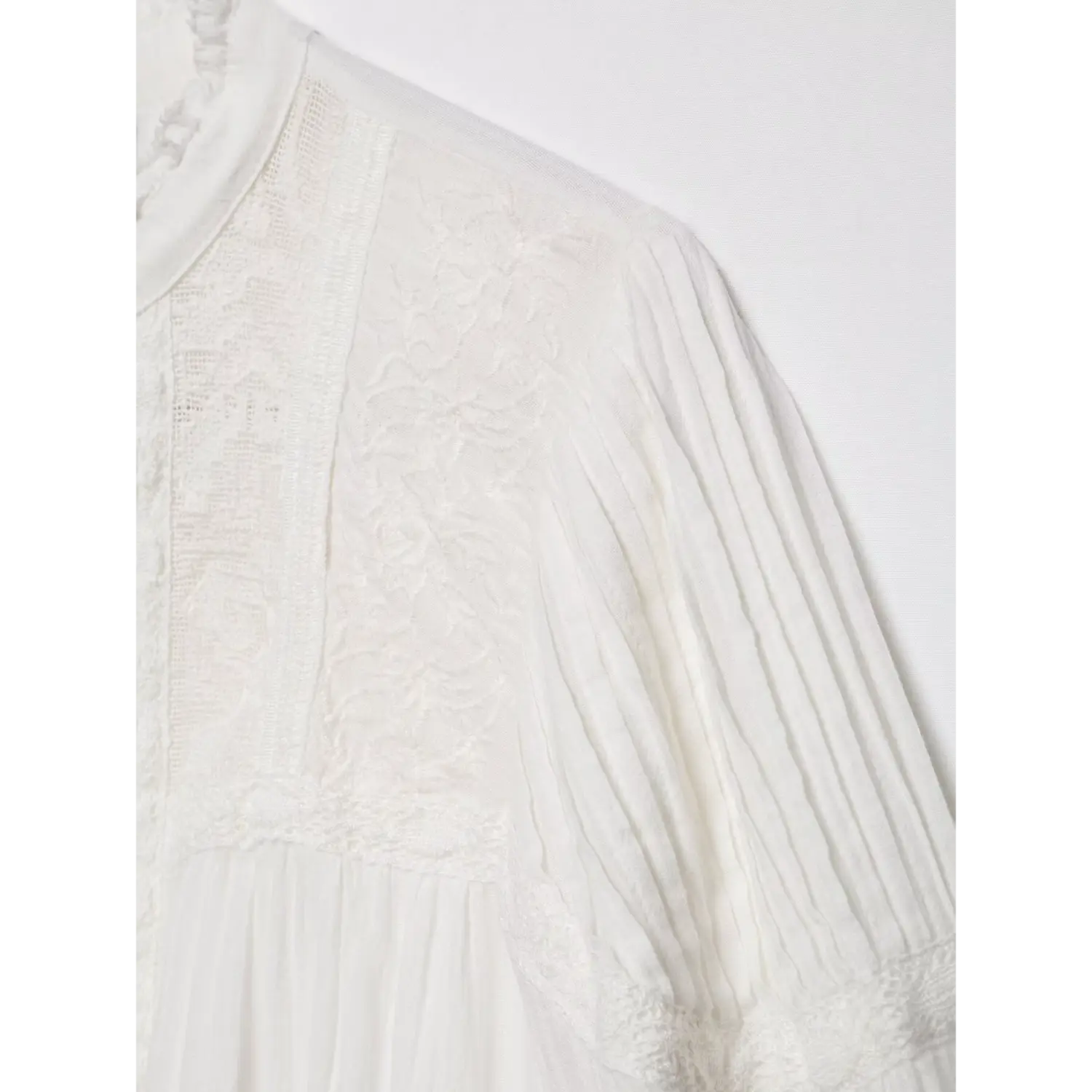 Fabric close-up of shoulder mesh panel, intricate floral embroidery combined with vertical textured stripe fabric