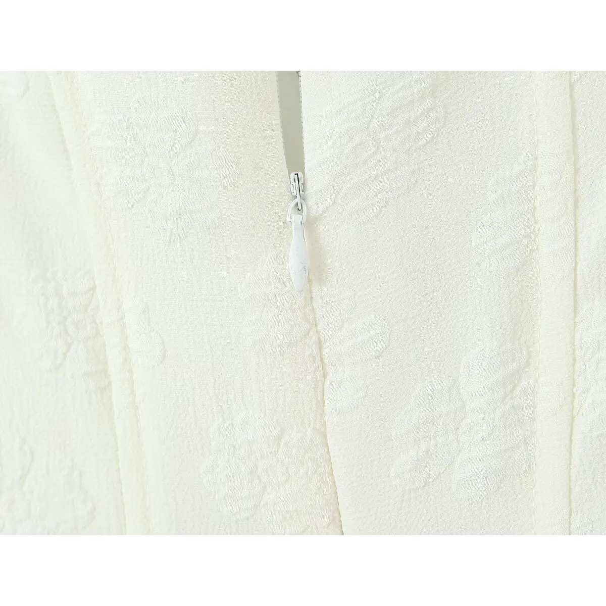 Close-up of the invisible center-back zipper, integrated into the textured white bodice.