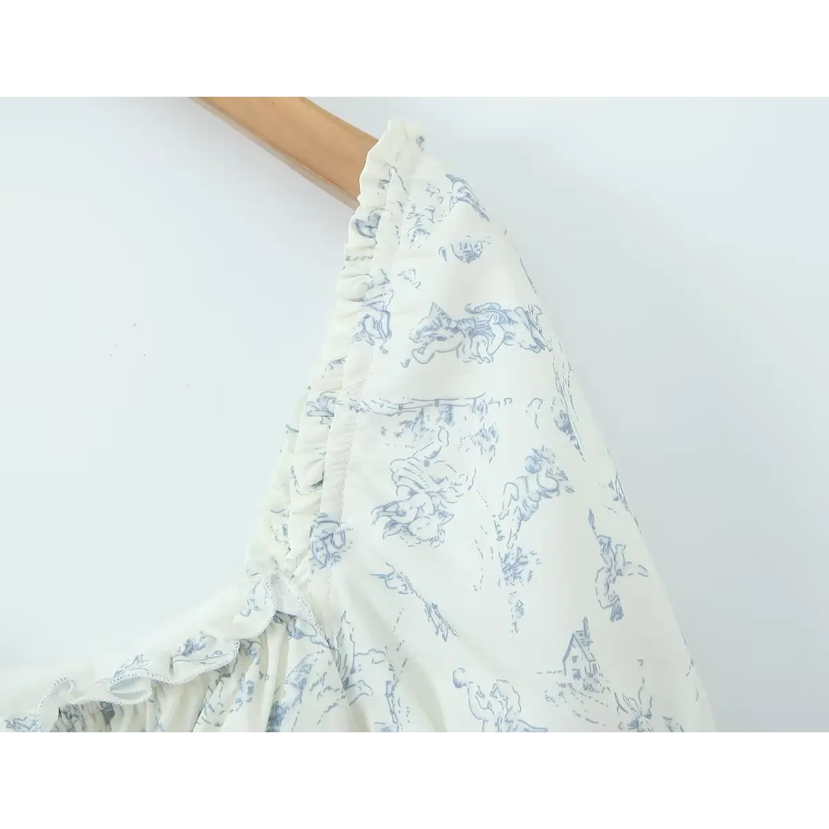 Close-up of the puffed sleeve and neckline, showing the delicate blue angel print and ruffled trim.