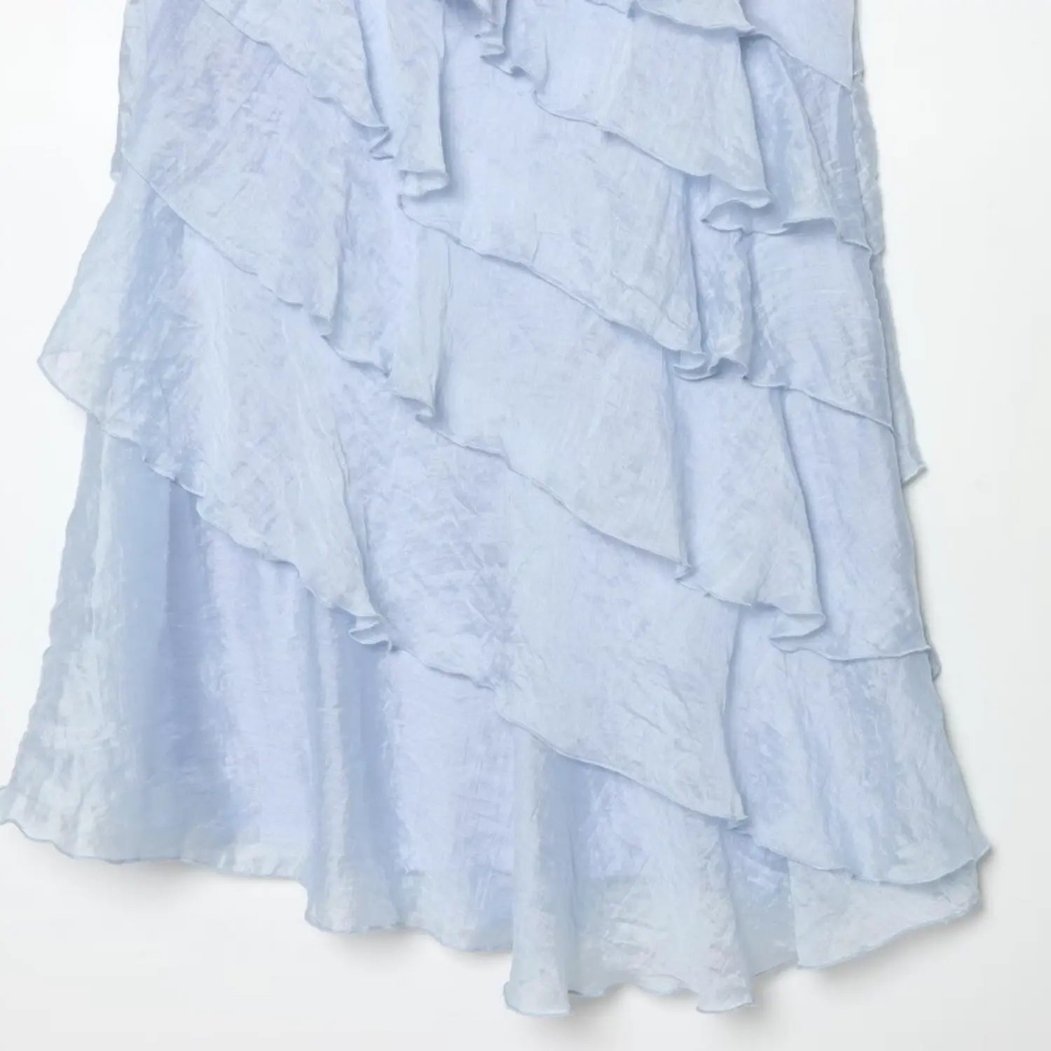 Close-up of diagonal uneven ruffle layers on light blue mini dress, waterfall cascading frill stitching detail