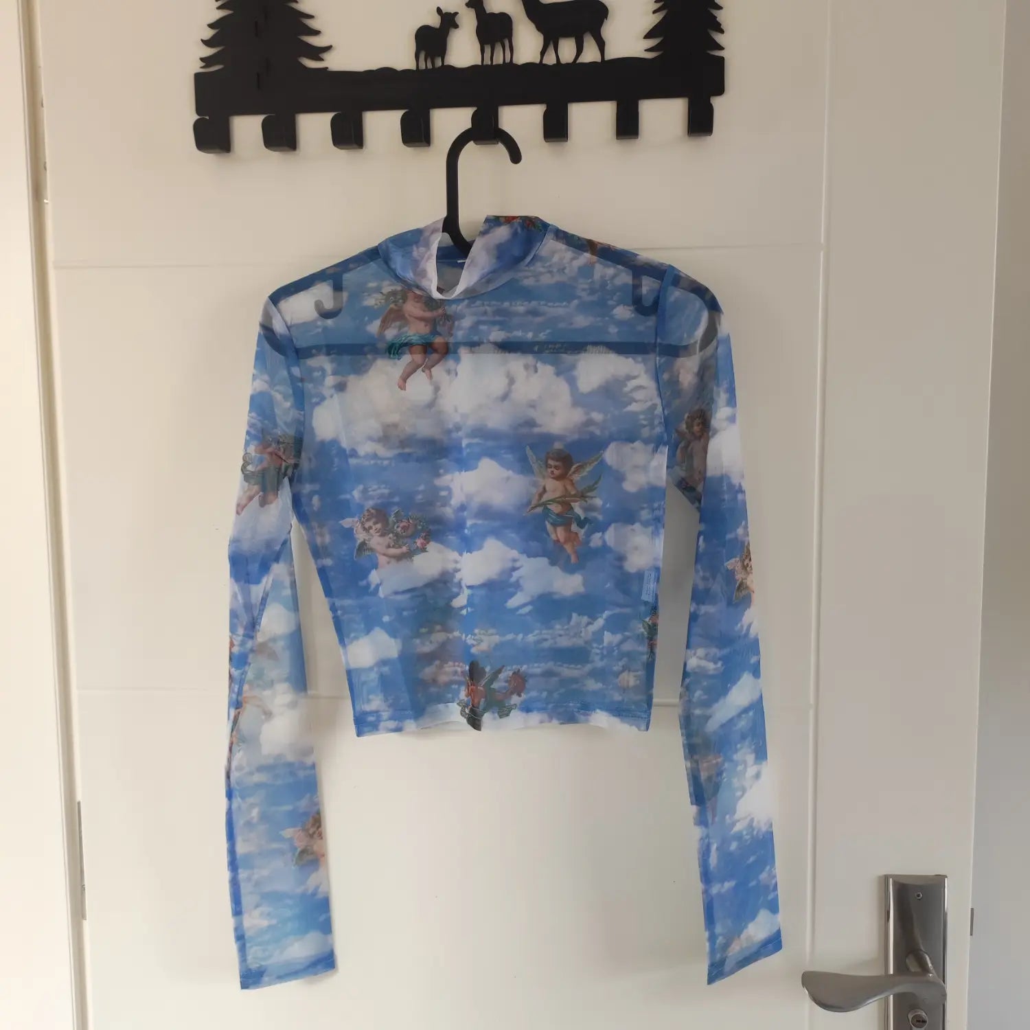 Hanging front view blue sheer mesh cropped turtleneck long sleeve top with all‑over angel cloud print