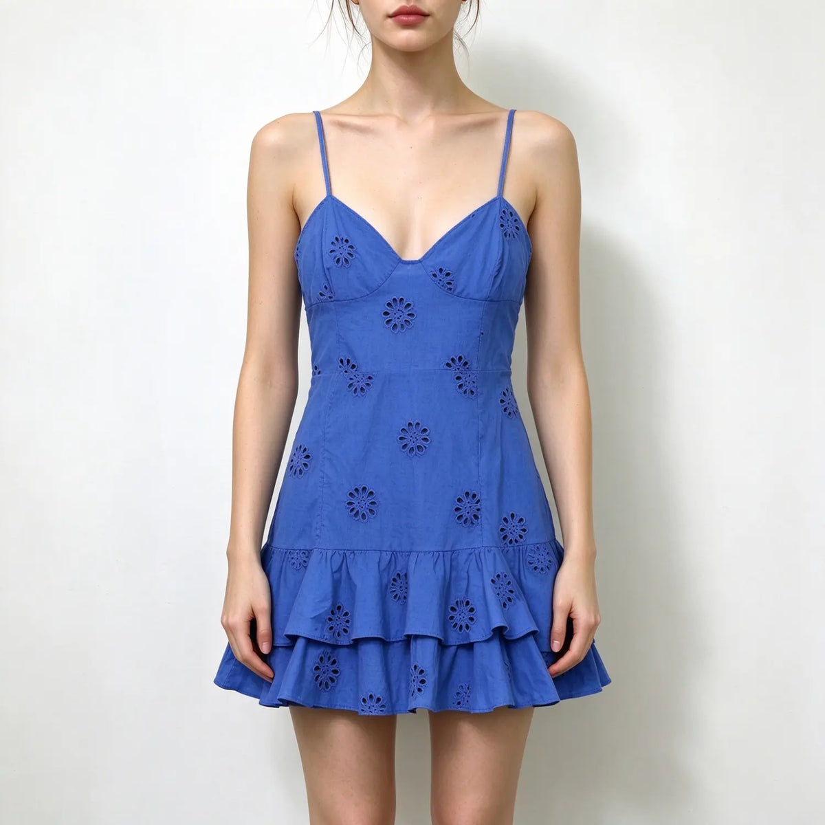 Model wearing blue eyelet lace spaghetti strap mini dress with v neck and double ruffle hem, plain white background