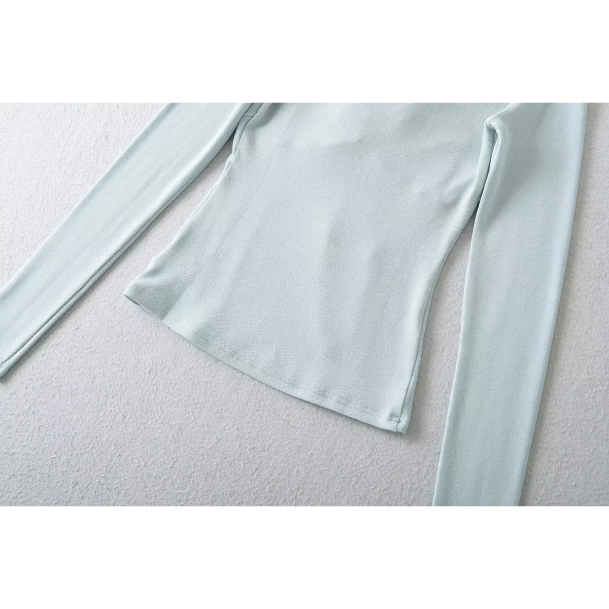 Macro closeup of fine overlock stitching on hem of blue ribbed knit top