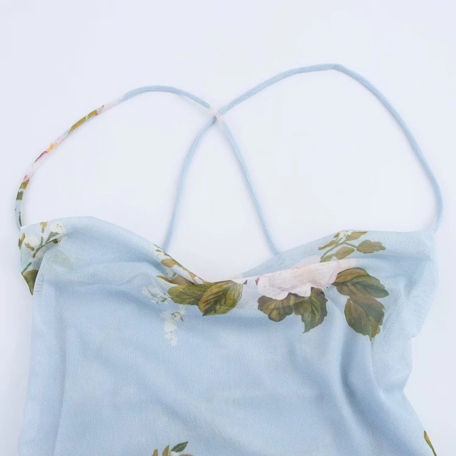 Close‑up of cowl neckline and thin criss‑cross spaghetti straps on light blue floral mesh slip mini dress
