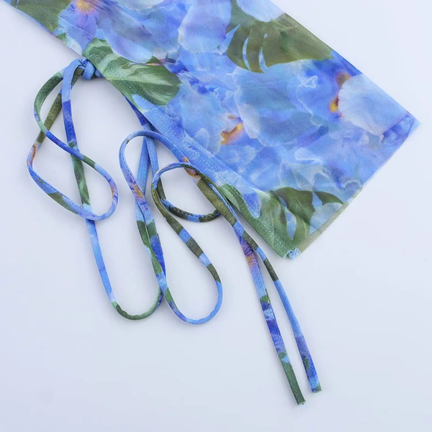 Close‑up of side adjustable drawstring ties on blue tropical floral mesh mini dress
