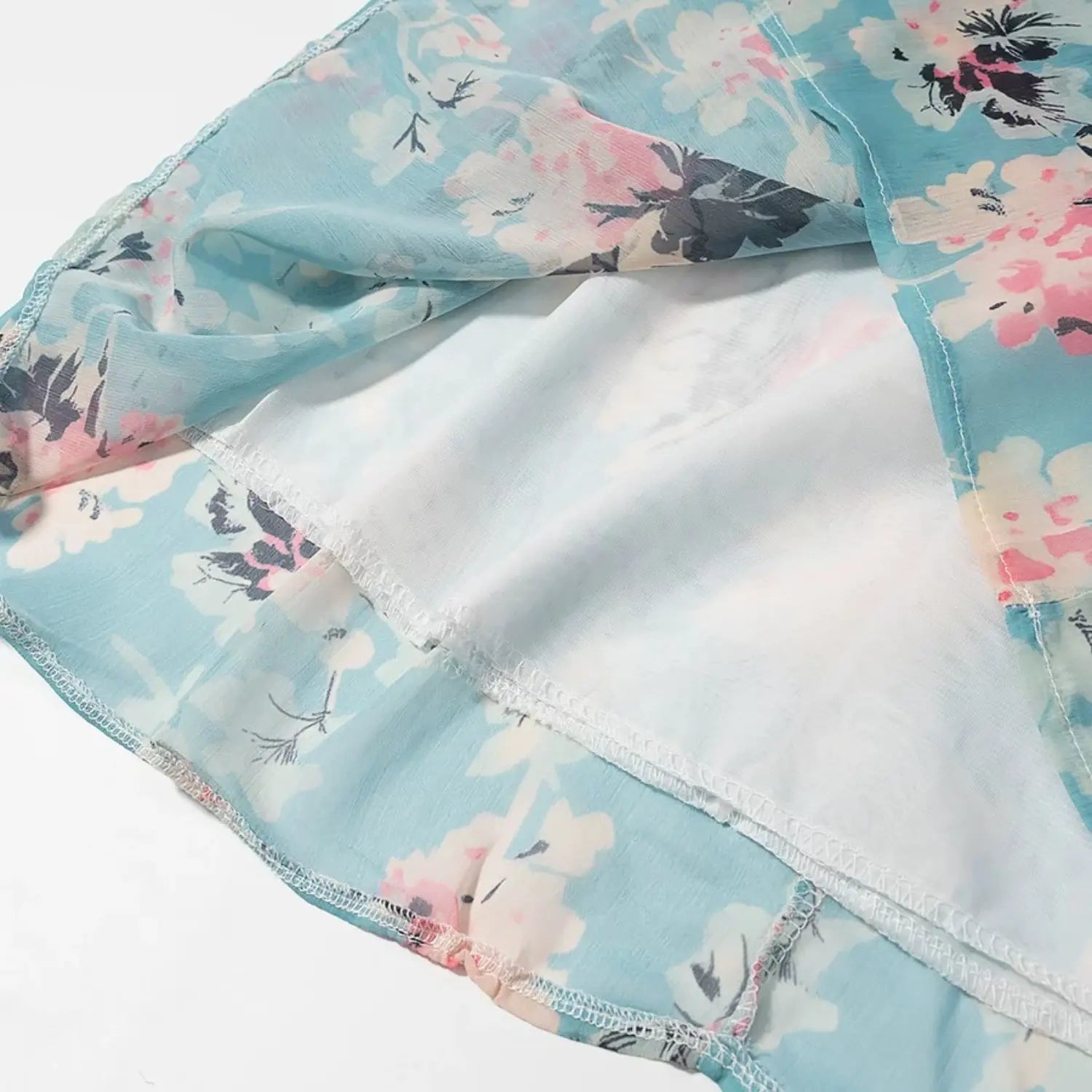 Close‑up of dress hem showing outer chiffon layer and attached white inner lining, neat stitching detail