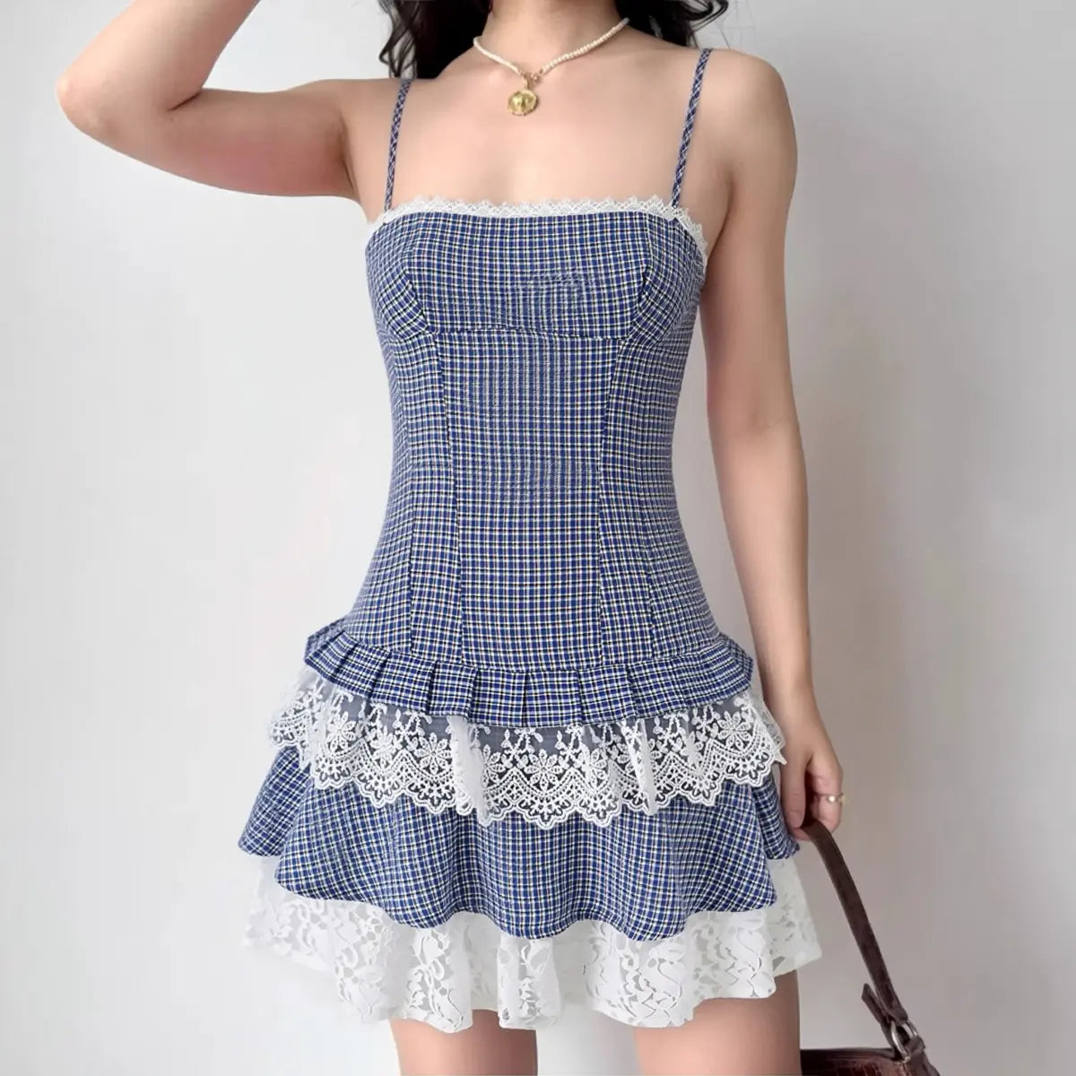 Woman wearing blue gingham cami tiered mini dress with lace trim, full front view