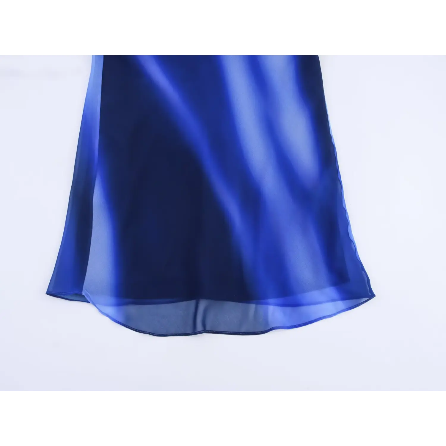 Flat lay close‑up of mermaid maxi hem, sheer chiffon layered hem, blue abstract gradient swirl print