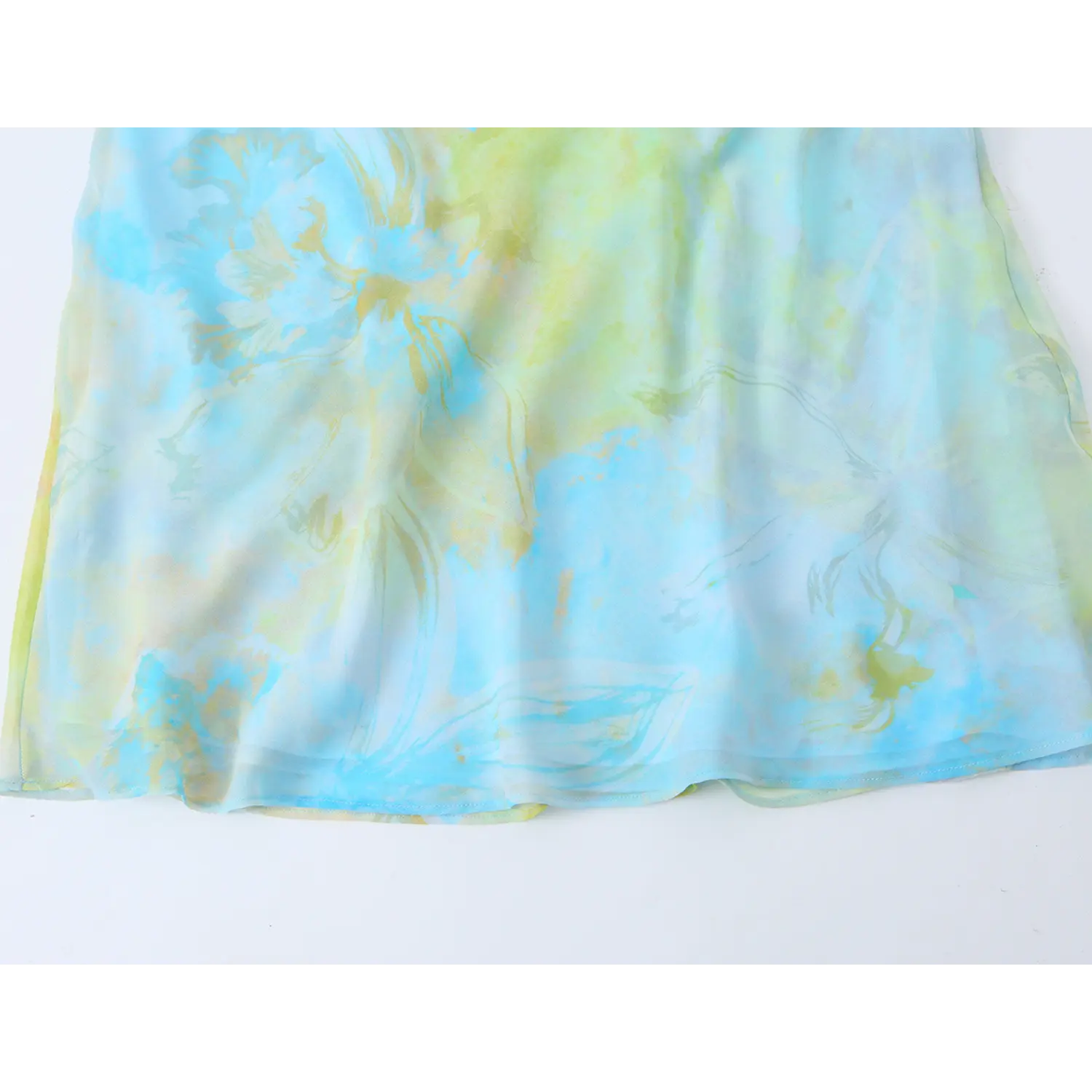 Close-up of skirt hem and floral print on blue green cowl neck slip midi dress
