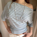 Front indoor lifestyle shot on model of striped off shoulder short sleeve top, side ruched twist detail, casual cropped blouse