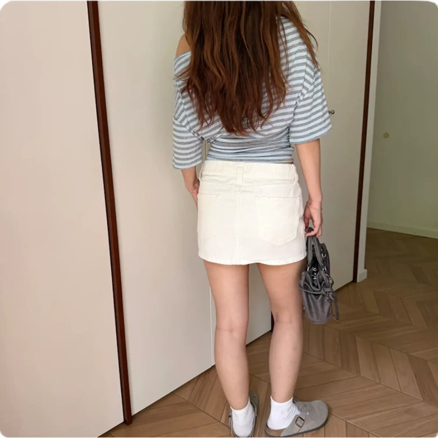 Back full body shot on model of striped off shoulder short sleeve top, loose fit back silhouette, twisted side hem detail