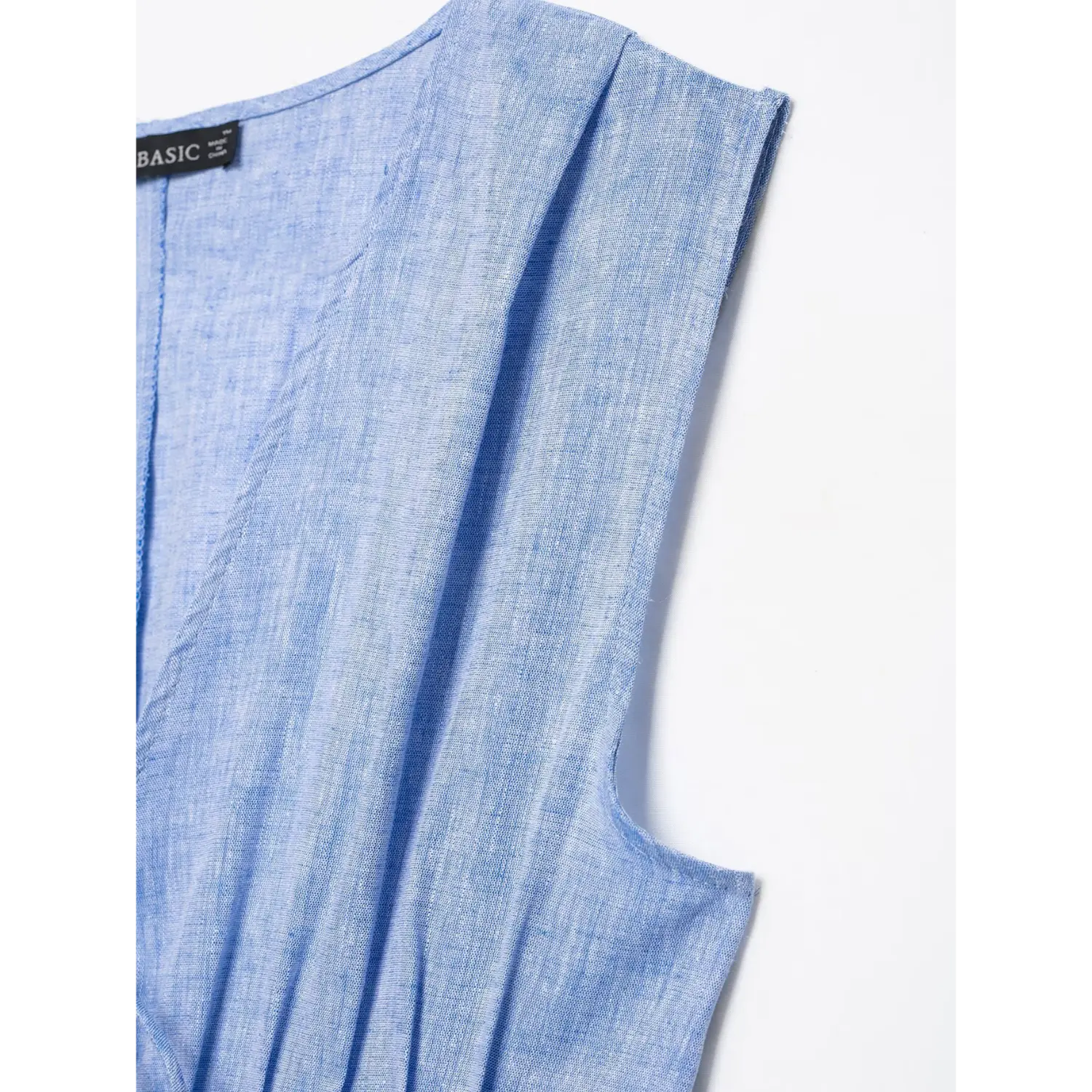 Close‑up shoulder armhole and pleated stitching, textured blue linen woven fabric