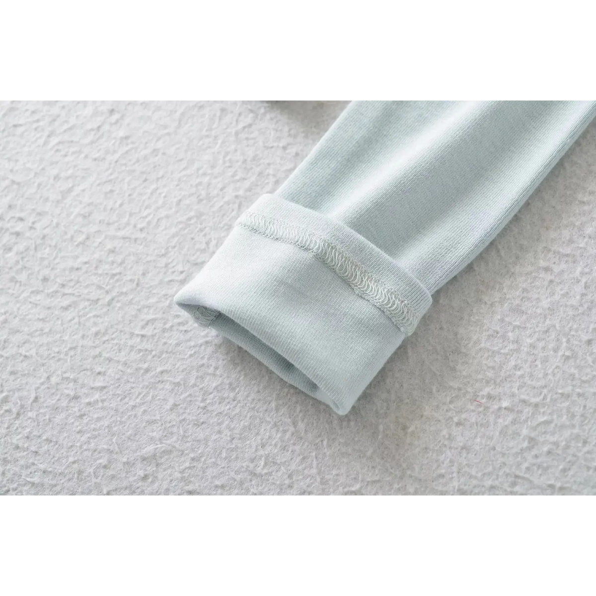 Close up of sleeve cuff with fine stitching on blue fitted ribbed knit top