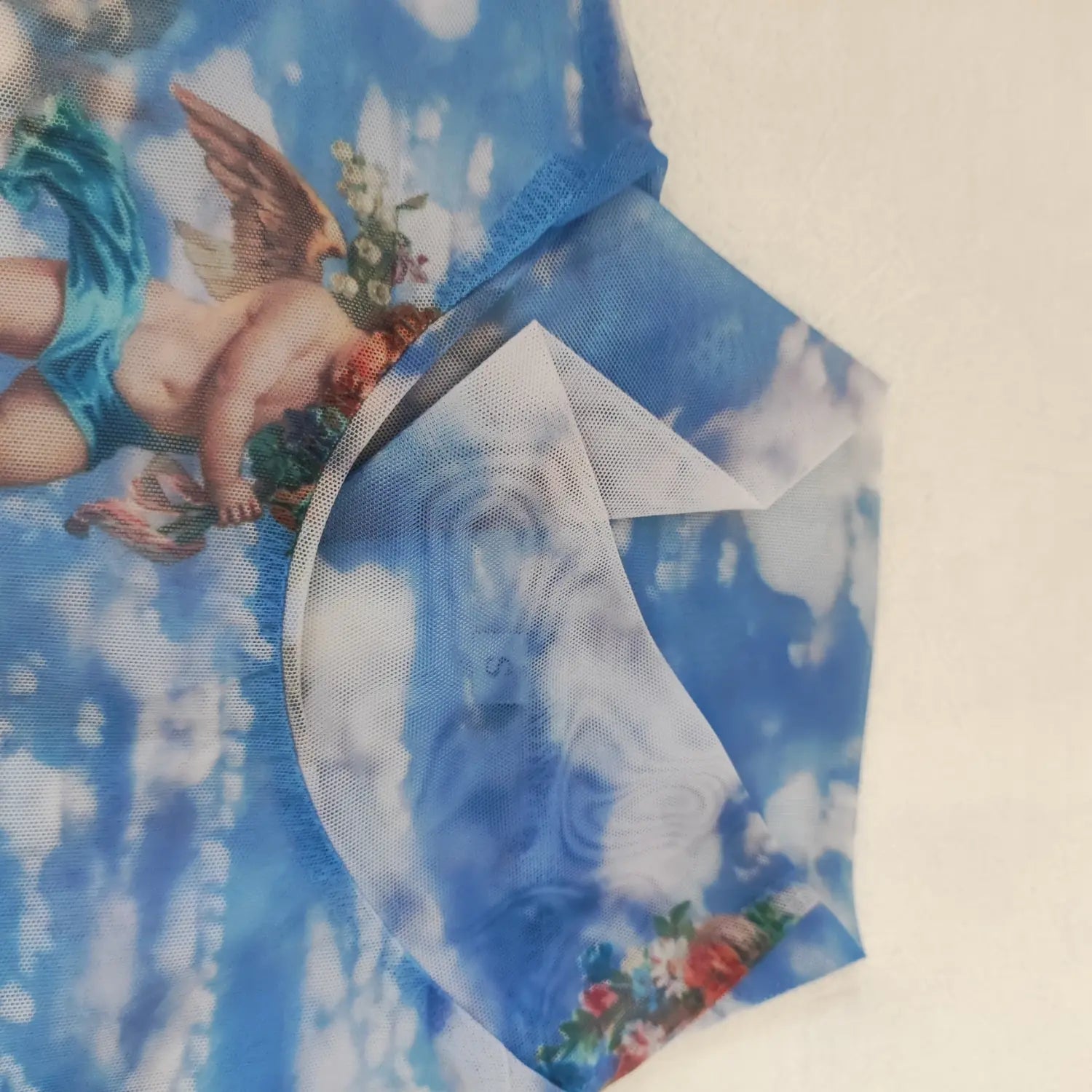 Close‑up turtleneck collar finished seam and mesh fabric of vintage cherub sky print long sleeve top