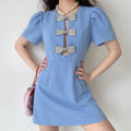 Model wearing blue mini dress, three rhinestone bows front keyhole cutout, puff short sleeves, complete outfit styling