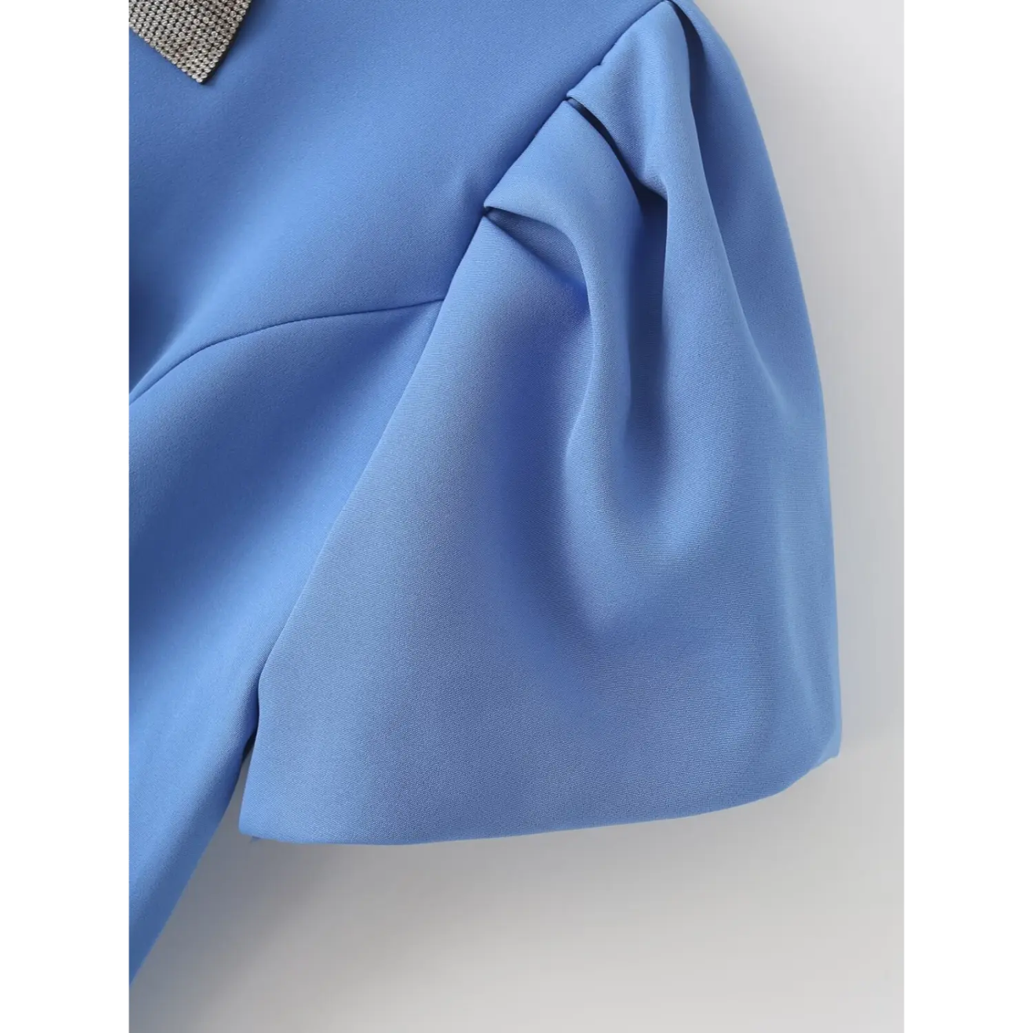 Close‑up of puff short sleeve pleat construction, smooth blue woven fabric shoulder detail