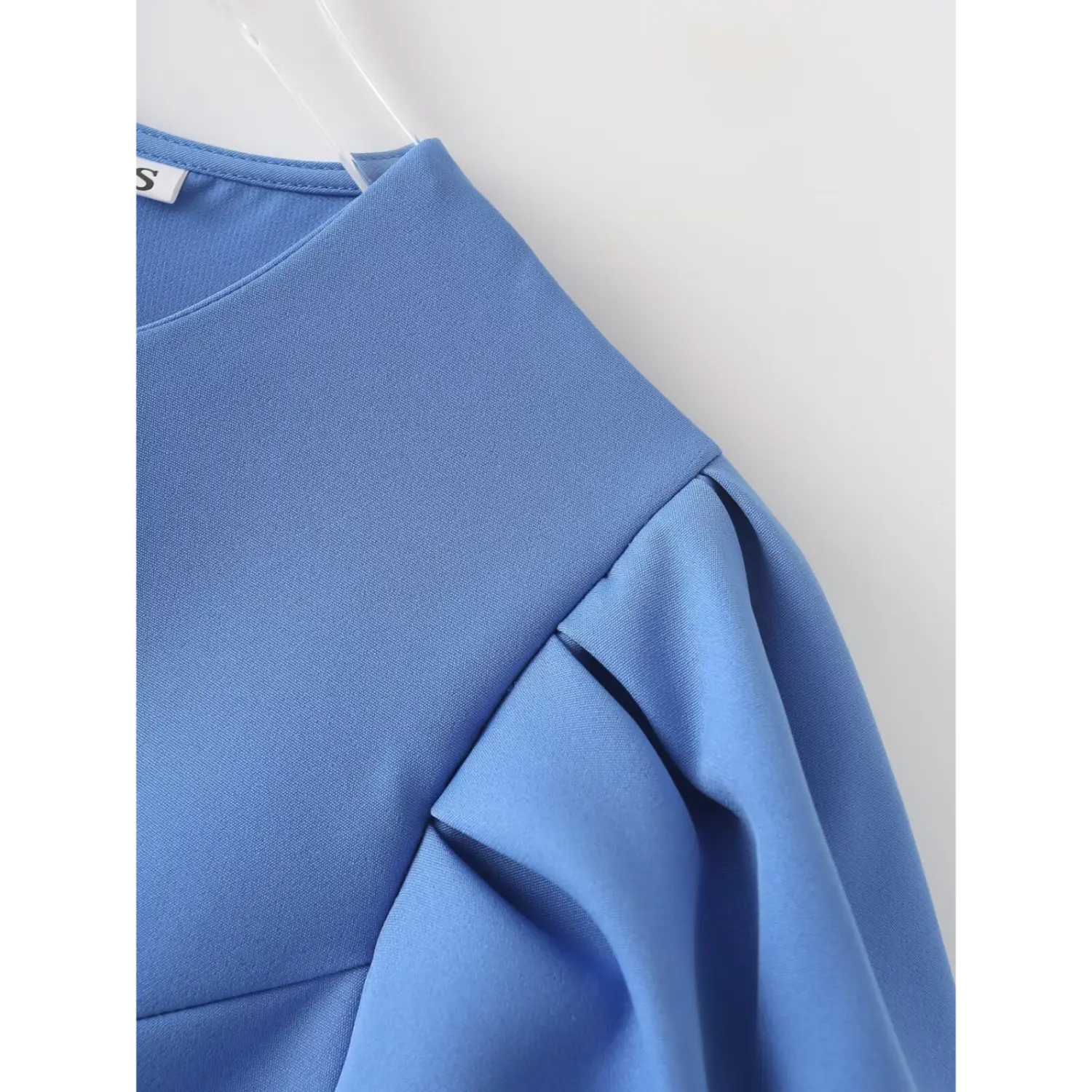 Close‑up shoulder and puff short sleeve, pleated sleeve construction, smooth blue woven fabric texture