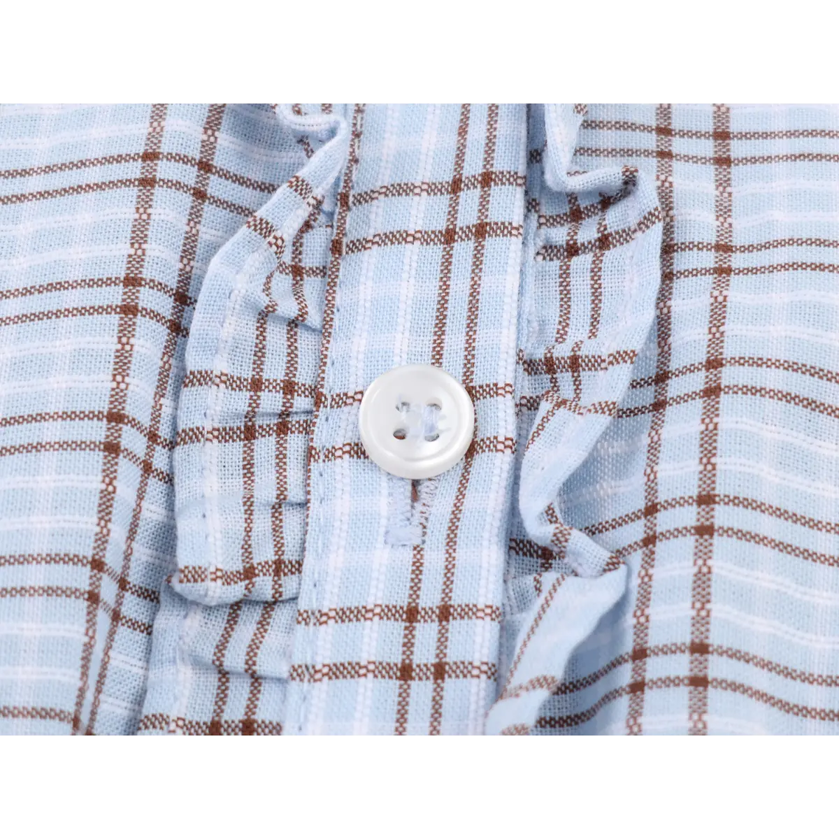 Close-up of the dress's white button and ruffled trim on the front placket.