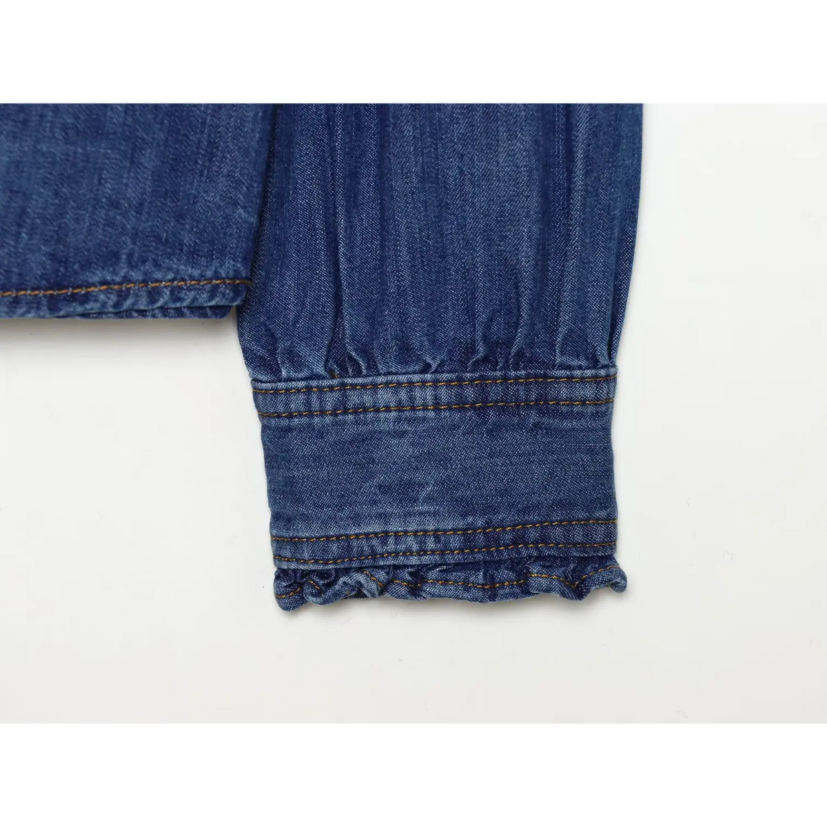 Close-up of ruffled cuff with double white buttons