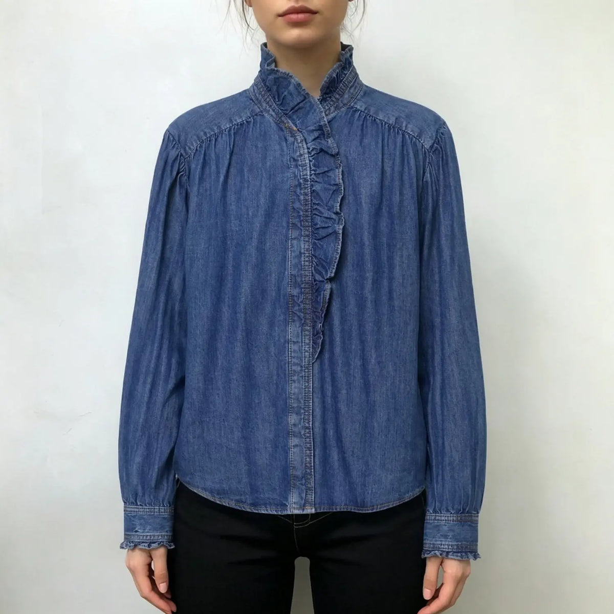 Model wearing blue ruffle collar denim shirt with black slim jeans