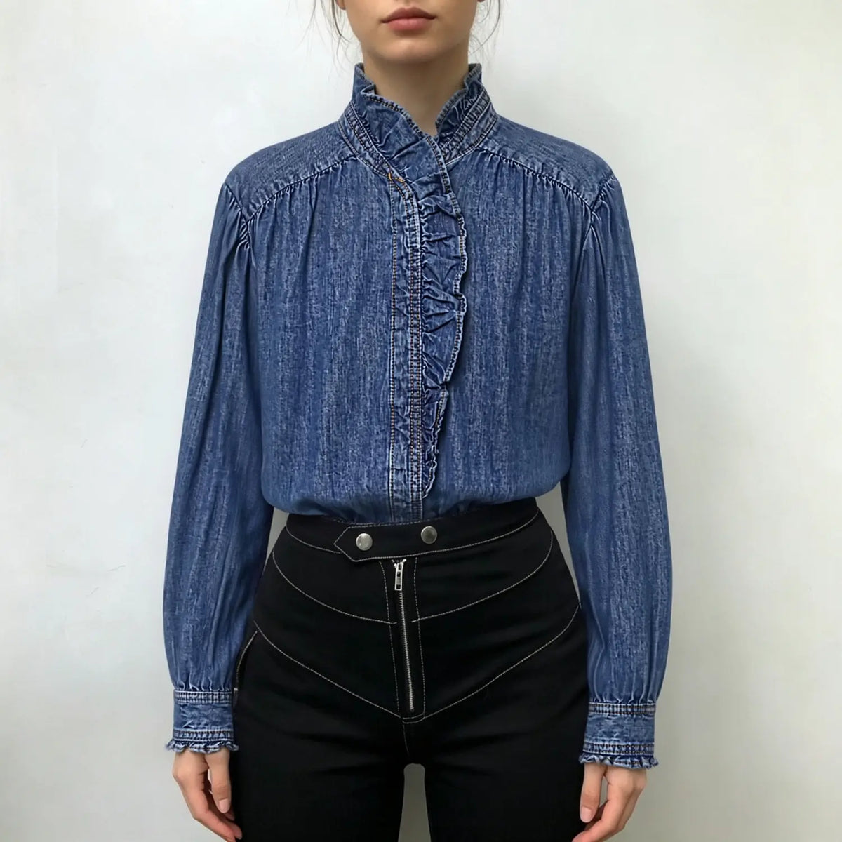 Model wearing blue ruffle collar denim shirt with black high-waist trousers