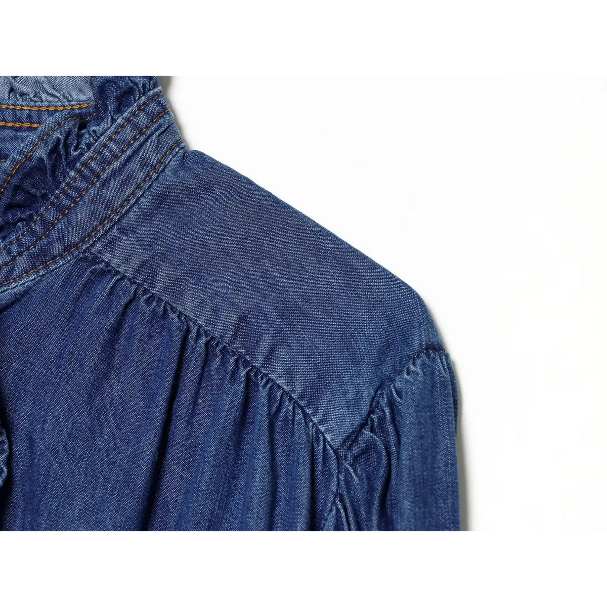 Close-up of gathered shoulder yoke on blue denim shirt