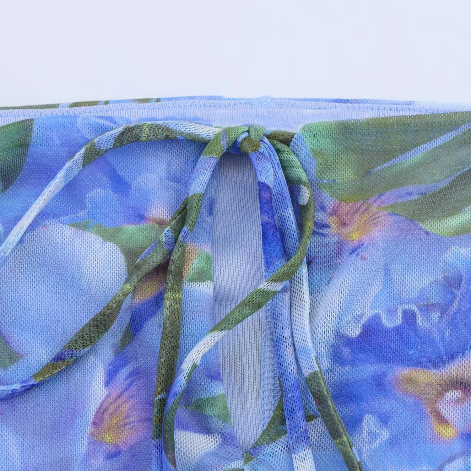 Close‑up of back tie‑up detail on blue tropical floral off‑shoulder mesh mini dress, printed fabric drawstring and stitching view