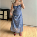 Straight front indoor mirror lifestyle photo of faded blue micro floral maxi slip dress, model gently lifting skirt hem to show sheer lightweight fabric, burgundy two-strap mary jane shoes