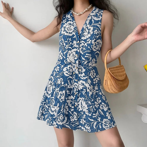 Lifestyle shot of a woman wearing the blue floral sleeveless dress, paired with a woven handbag