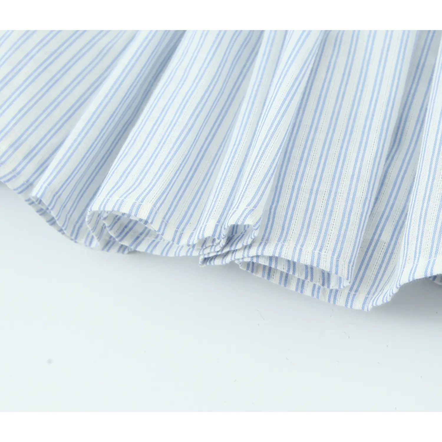 Close‑up dress hem detail, finished stitching on blue and white vertical striped lightweight fabric