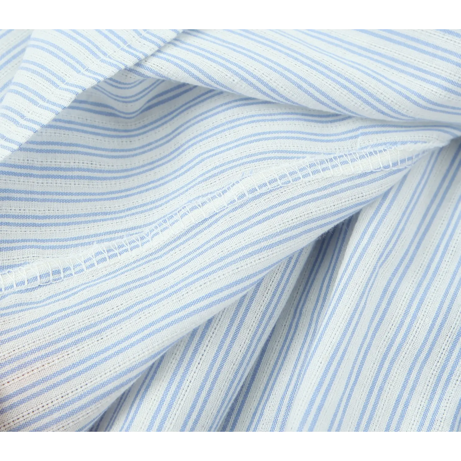 Close‑up interior overlock seam detail, blue white striped dress fabric, clean finished stitching