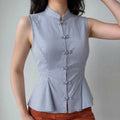 Front lifestyle shot on model of fitted chinese style sleeveless vest top, stand collar, frog buttons, flared peplum hem