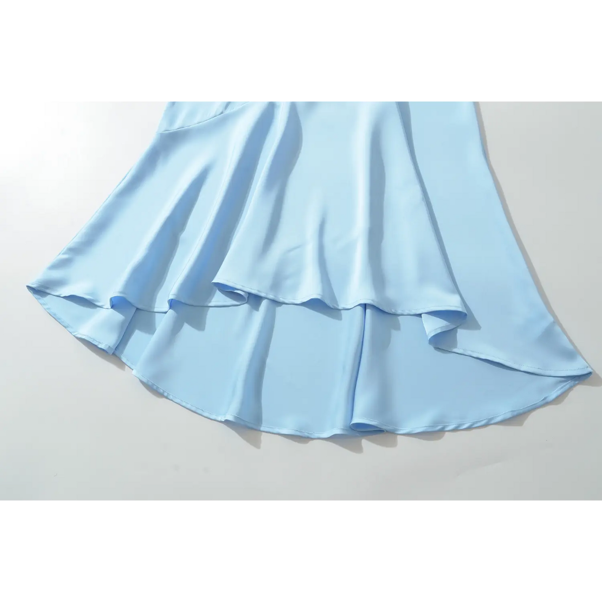 Close‑up of asymmetrical layered ruffle hem on blue satin maxi dress