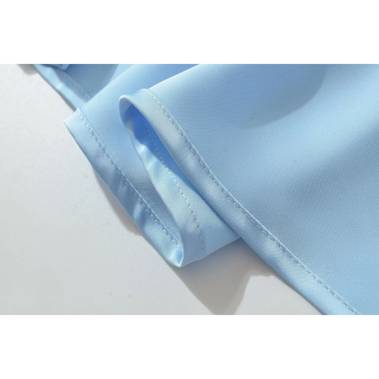 Close‑up of neat finished hem edge of blue satin maxi dress