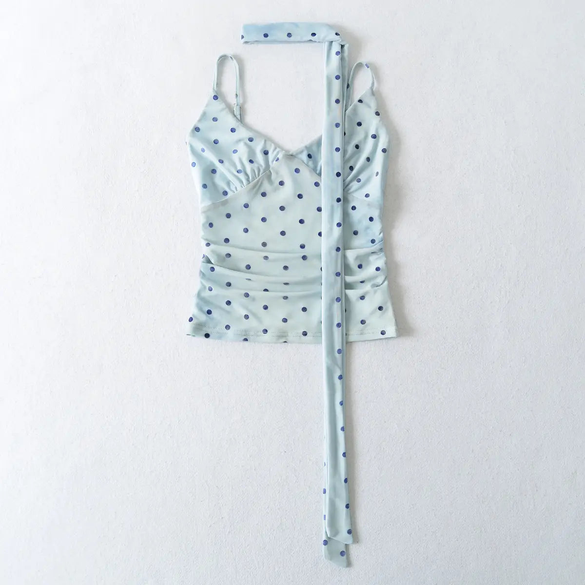 Light blue polka dot top with a long tie on a white background