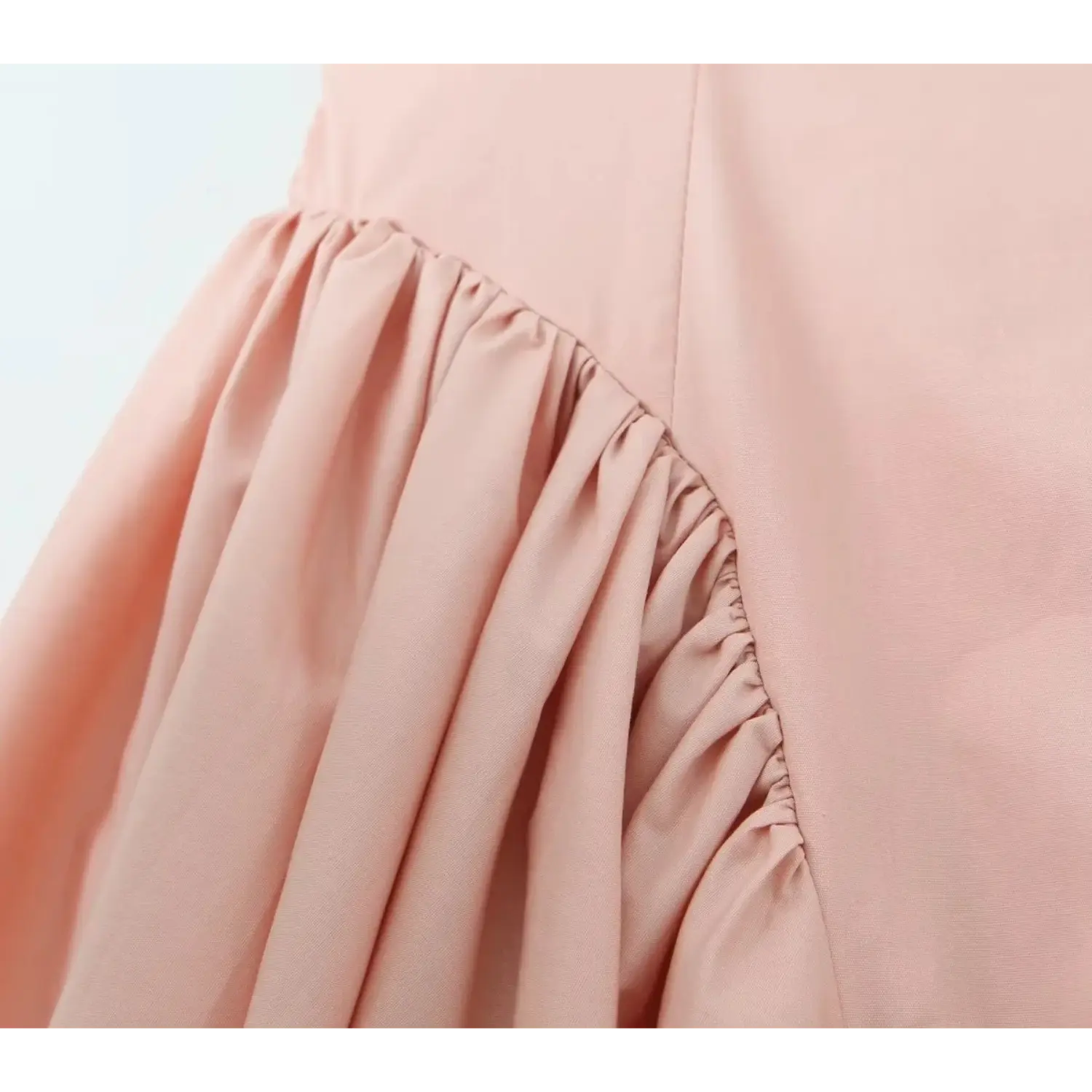 Macro close‑up of skirt gathering seam, neat stitching detail, soft blush pink woven fabric, ruched transition from fitted bodice to flare skirt