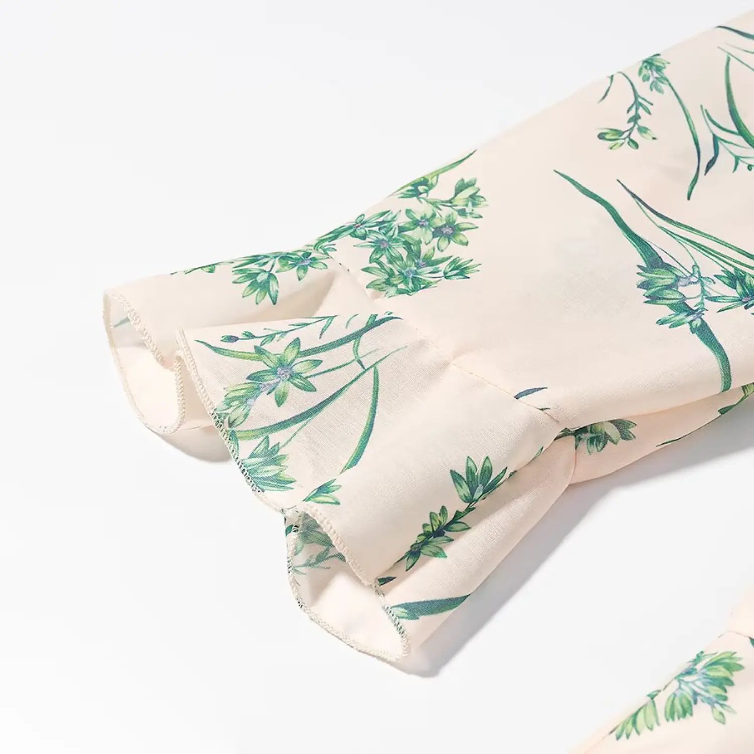 Close‑up detail of short sleeve ruffle cuff on blush green botanical printed dress