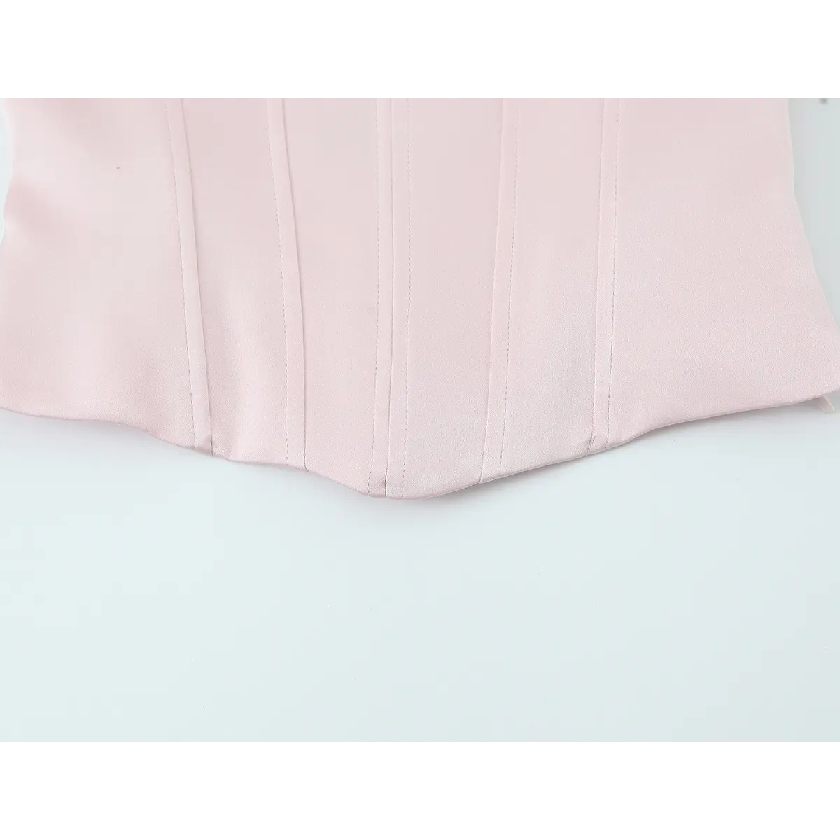 Front hem detail of the blush pink bustier top, showing the scalloped edge and evenly spaced boning seams