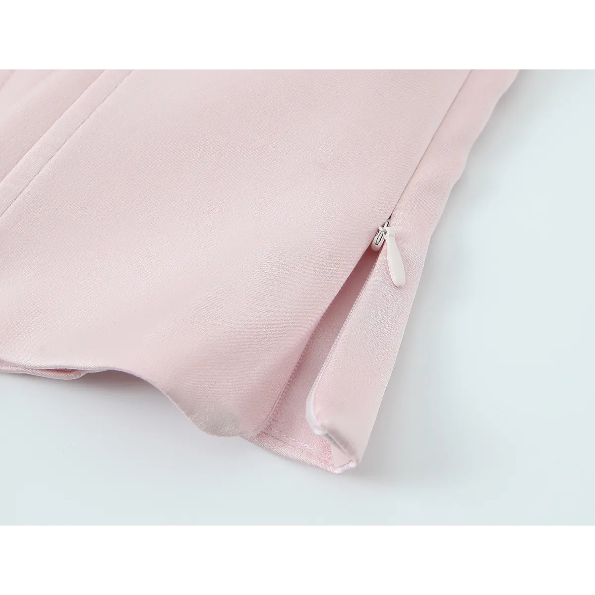  Close-up of the side zipper on the blush pink bustier top, featuring a matching pink pull and neatly finished seam