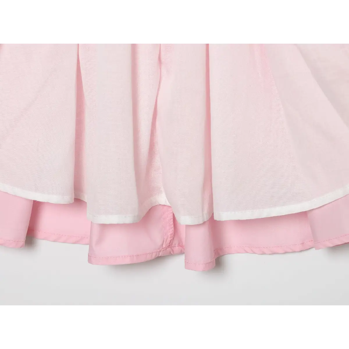  Double layer skirt close shot, outer pink woven fabric with white inner lining, finished serged hem stitching.