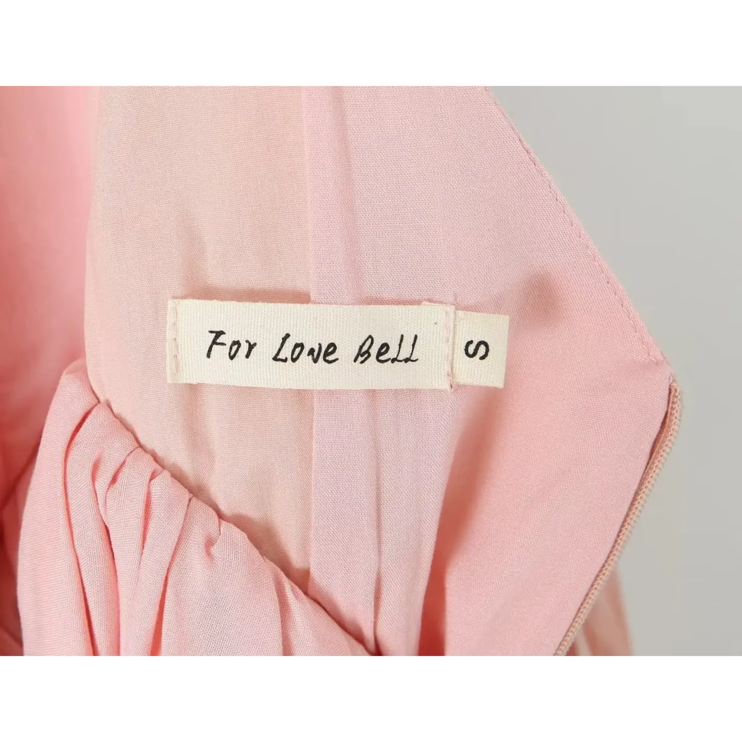 Close‑up inner clothing label, brand tag For Love Bell size S, stitched inside blush pink dress lining