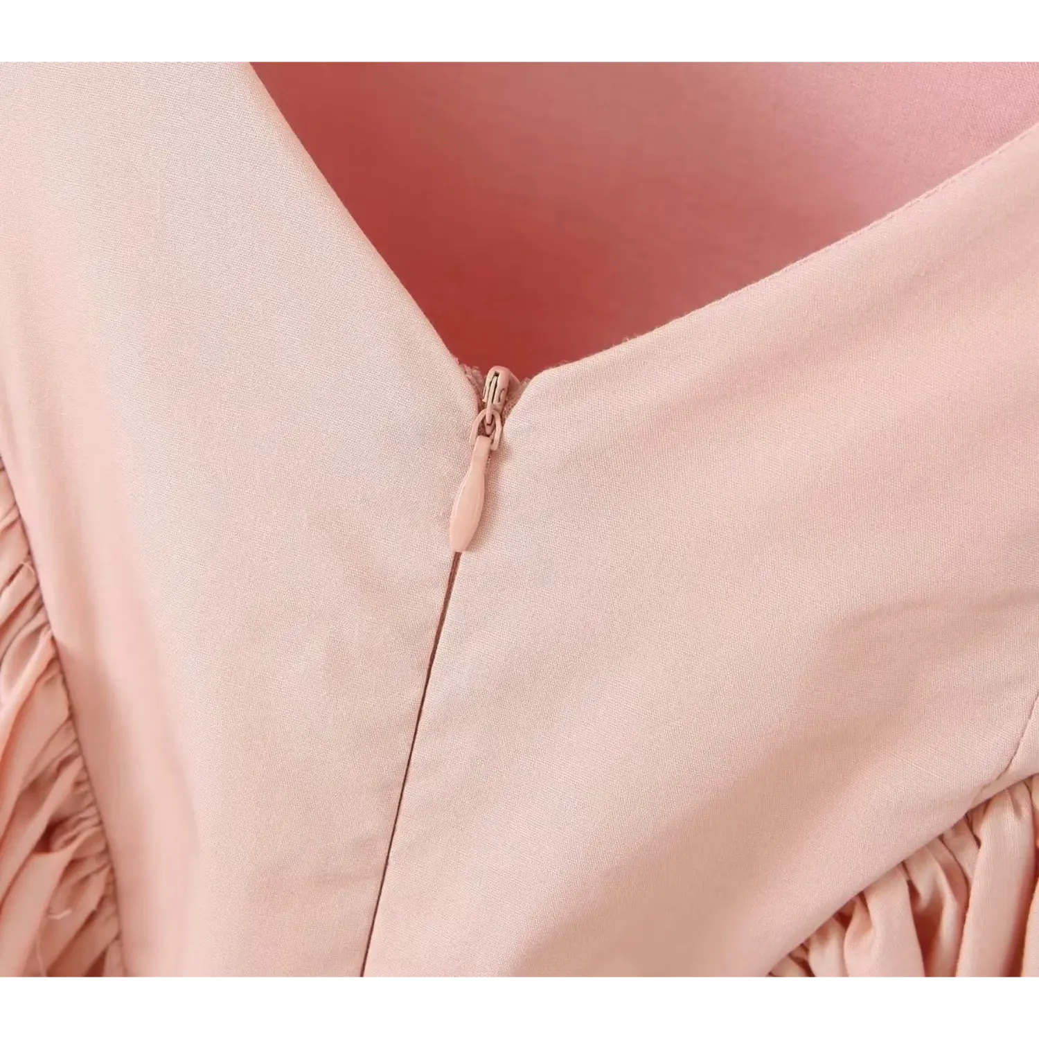 Macro close‑up of hidden invisible zipper on blush pink dress back, matching pink zipper pull, smooth woven fabric