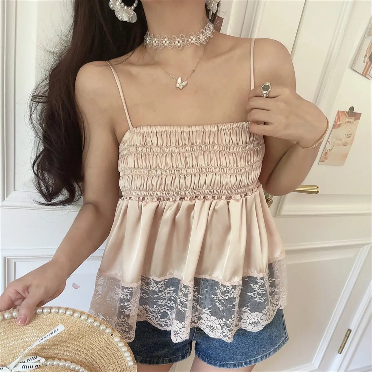 Angled view of the blush pink cami top, styled with denim shorts, showing the smocked bodice and lace hem detail