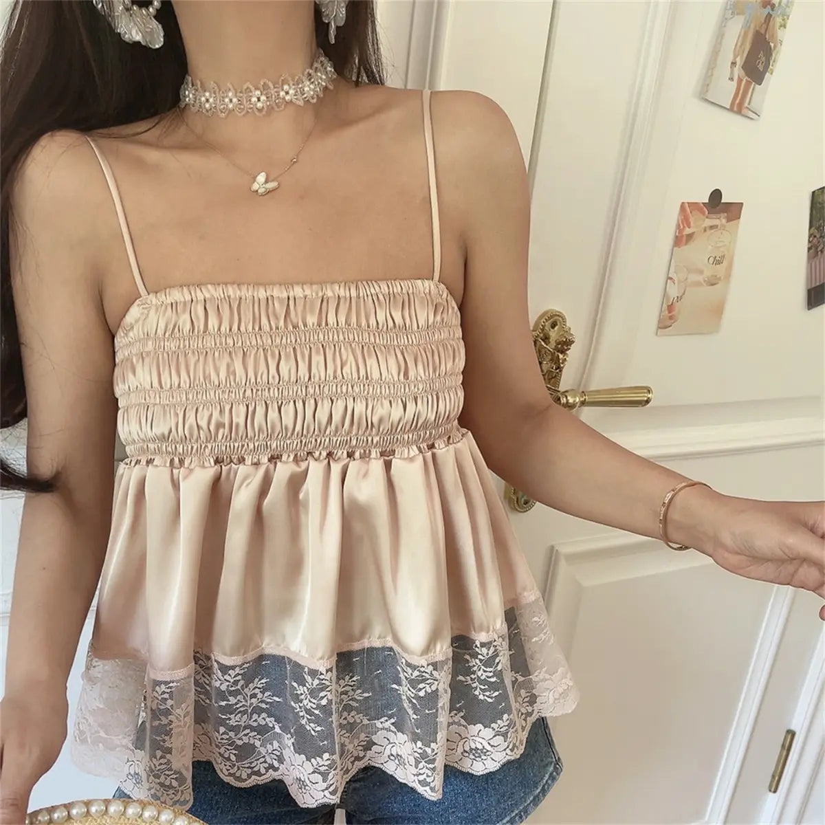 Front view of the blush pink lace-hem cami top, featuring smocked bodice, satin fabric, and floral lace trim at the hem
