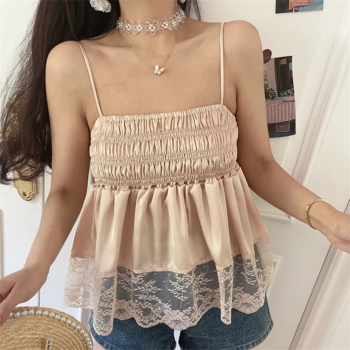 Side view of the blush pink cami top, highlighting the peplum silhouette and scalloped floral lace hem