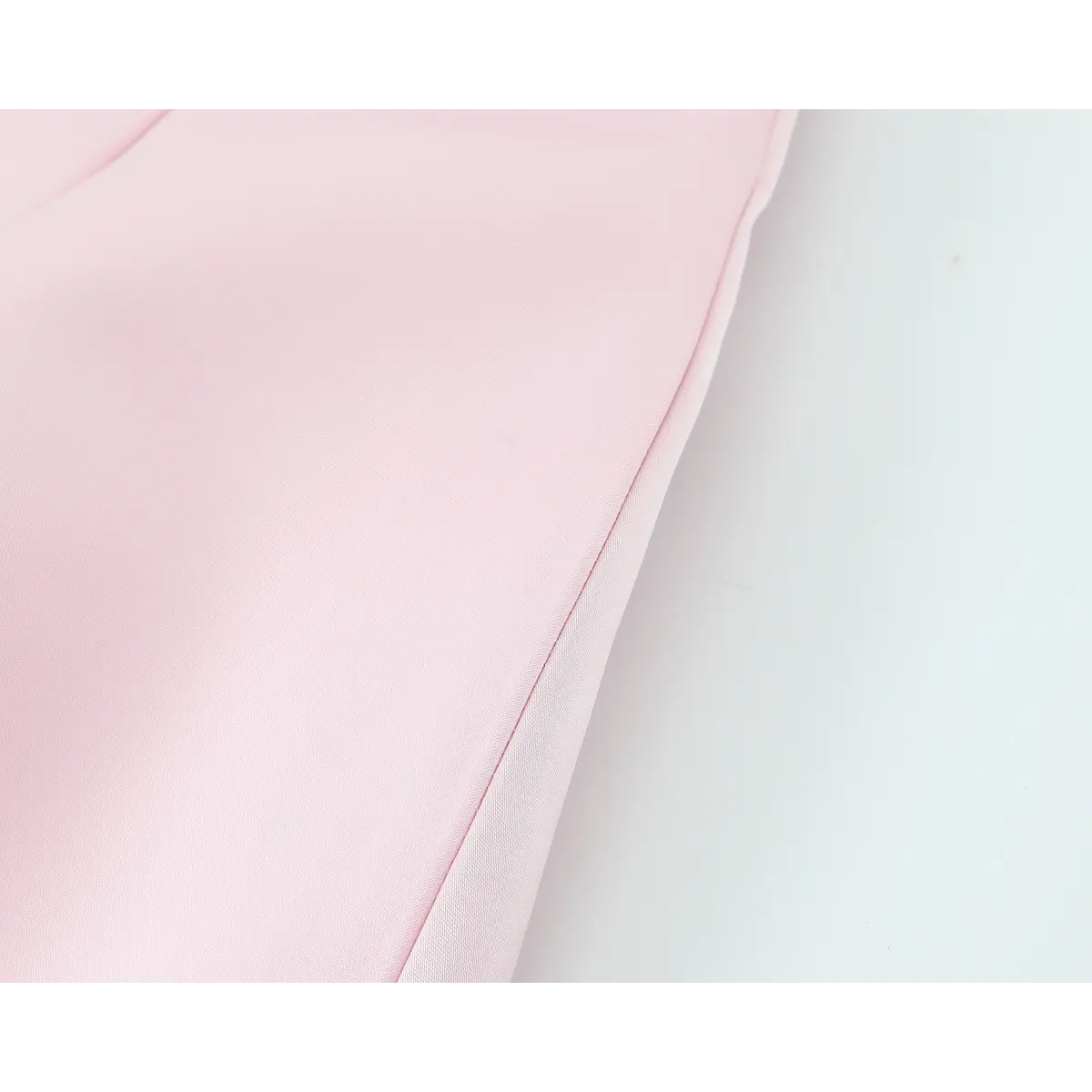 Close-up view of the skirt hem on a blush pink satin mini dress, showing the clean stitching and finished edge.