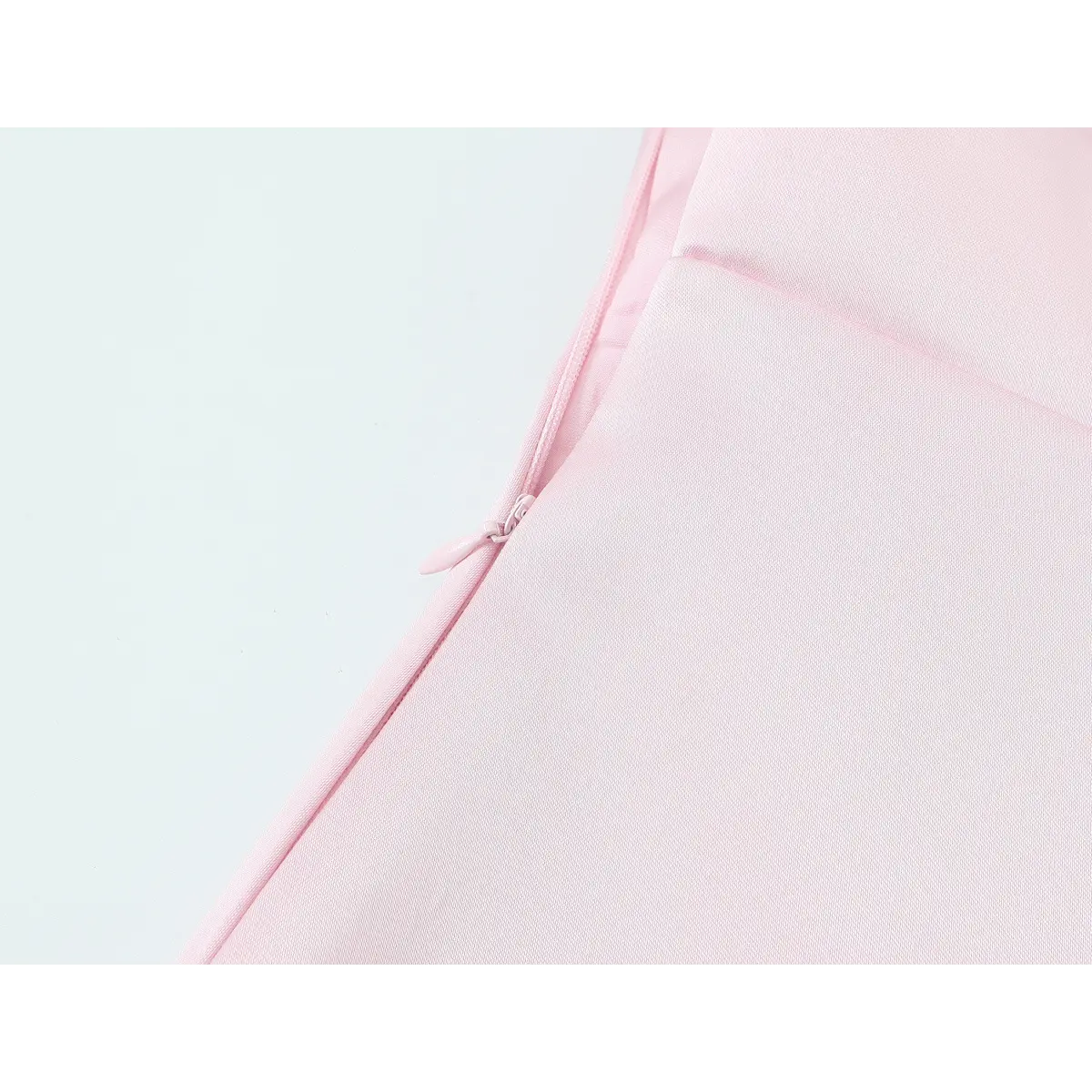 Close-up detail shot of the side zipper on a blush pink satin mini dress, showing the matching pink zipper pull and fabric construction.
