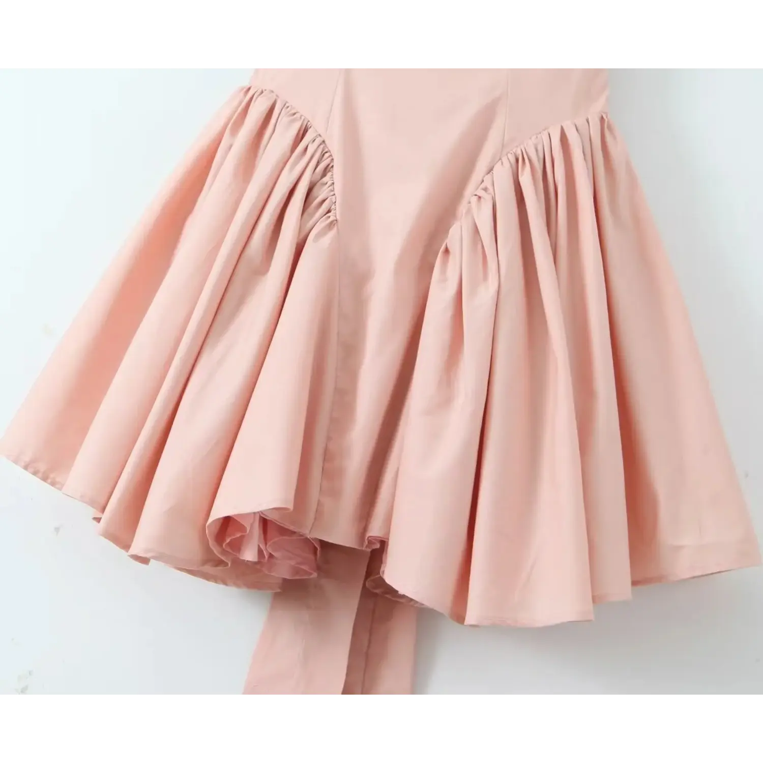 Partial shot of voluminous gathered flared skirt, high‑waist seam, pleated fabric creating full skater silhouette, long hanging back sash