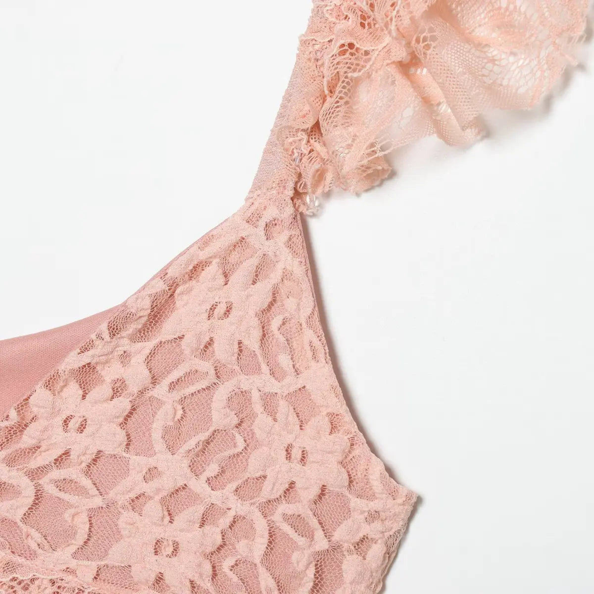 Close-up of the ruffled lace strap on the blush pink dress, showing the floral lace pattern and V-neckline