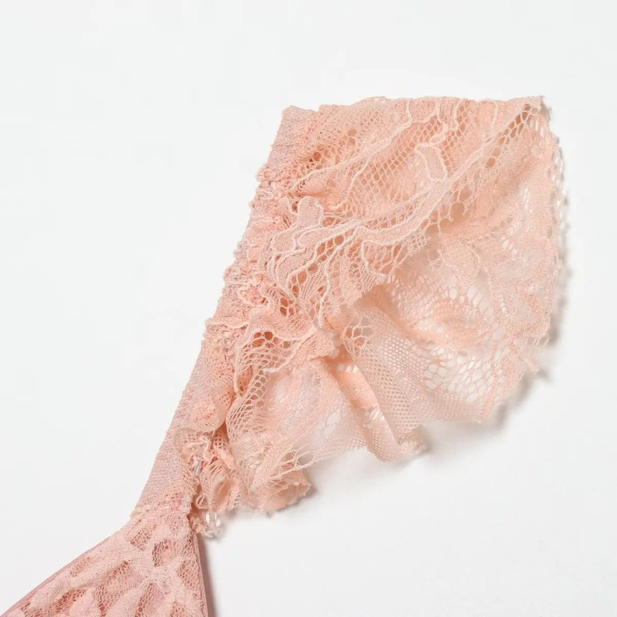 Close-up of the ruffled lace strap on the blush pink dress, showing the layered lace construction